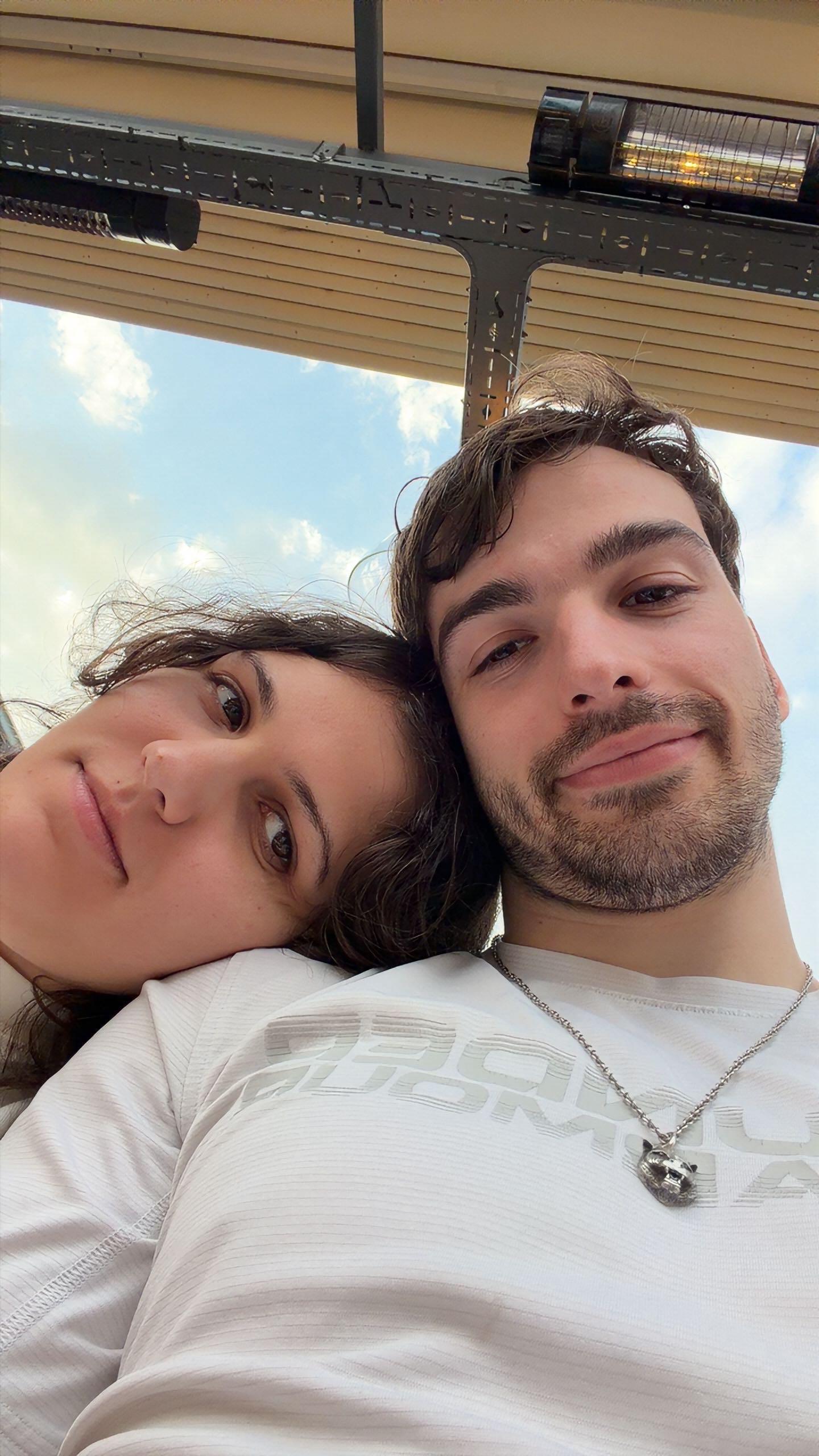 Asya resting her head on Jan's shoulder under an open sky